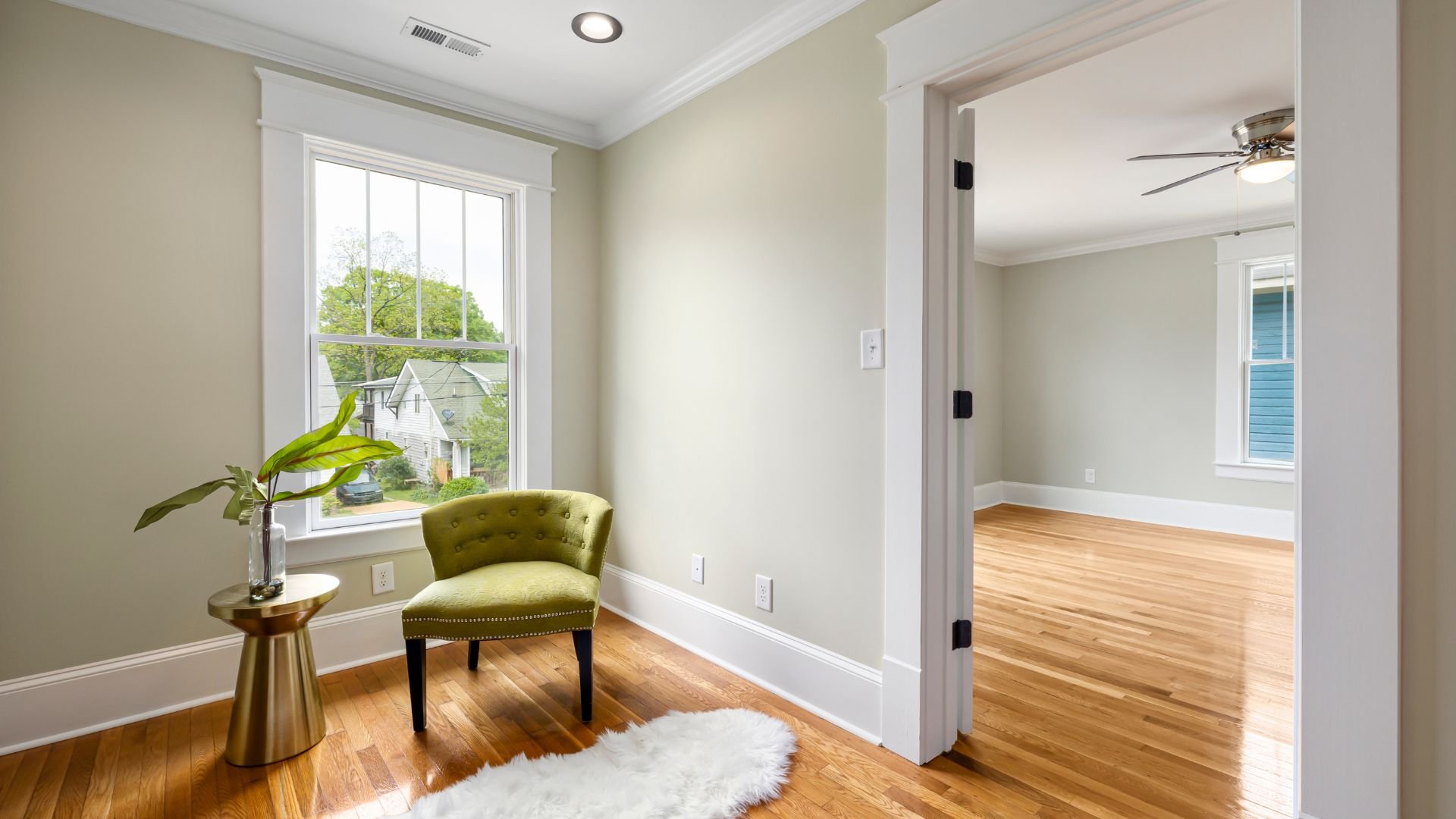 Bright room with green chair, side table, plant, and hardwood floors