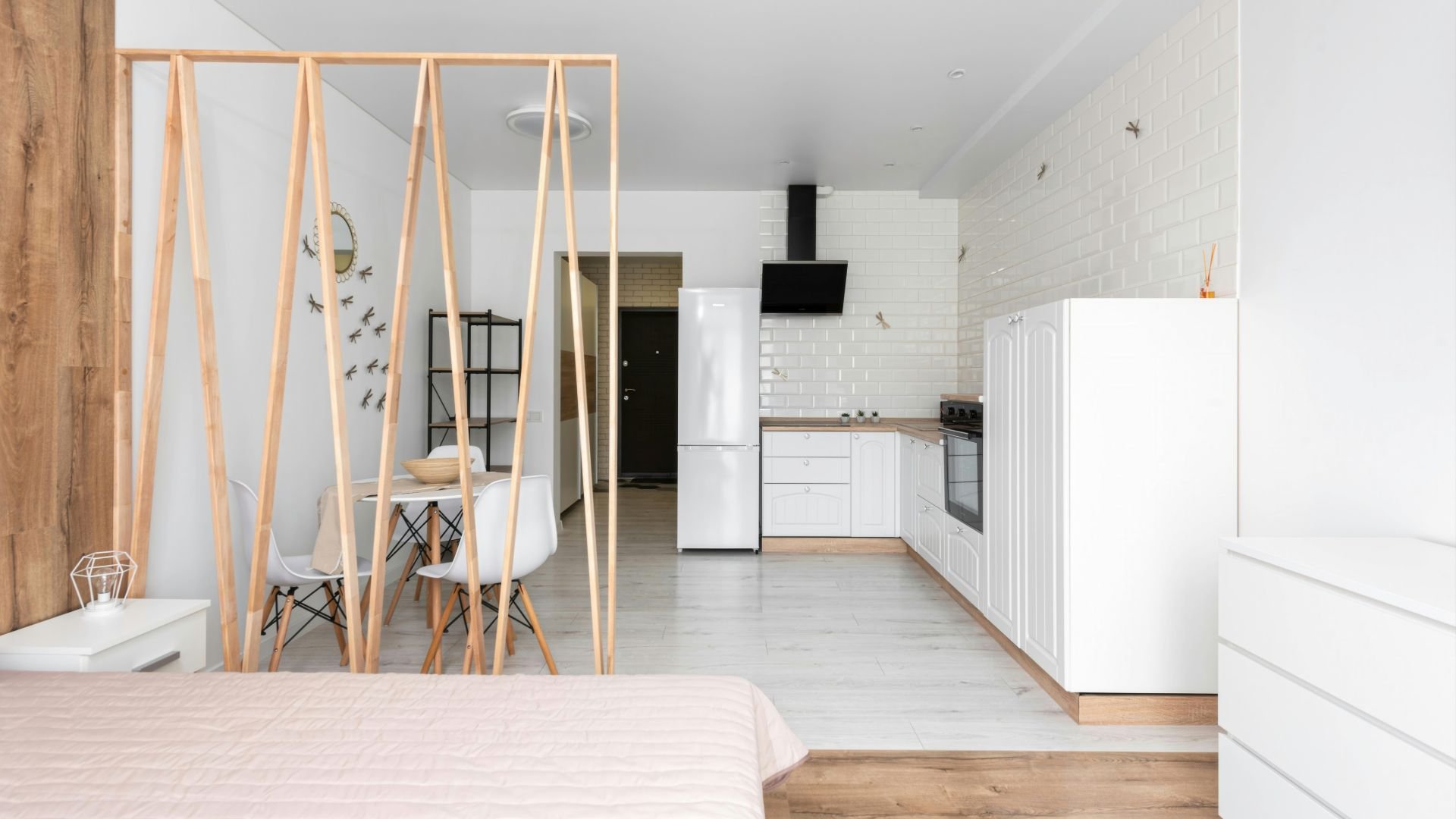 Minimalist studio apartment with wooden dividers and white kitchen