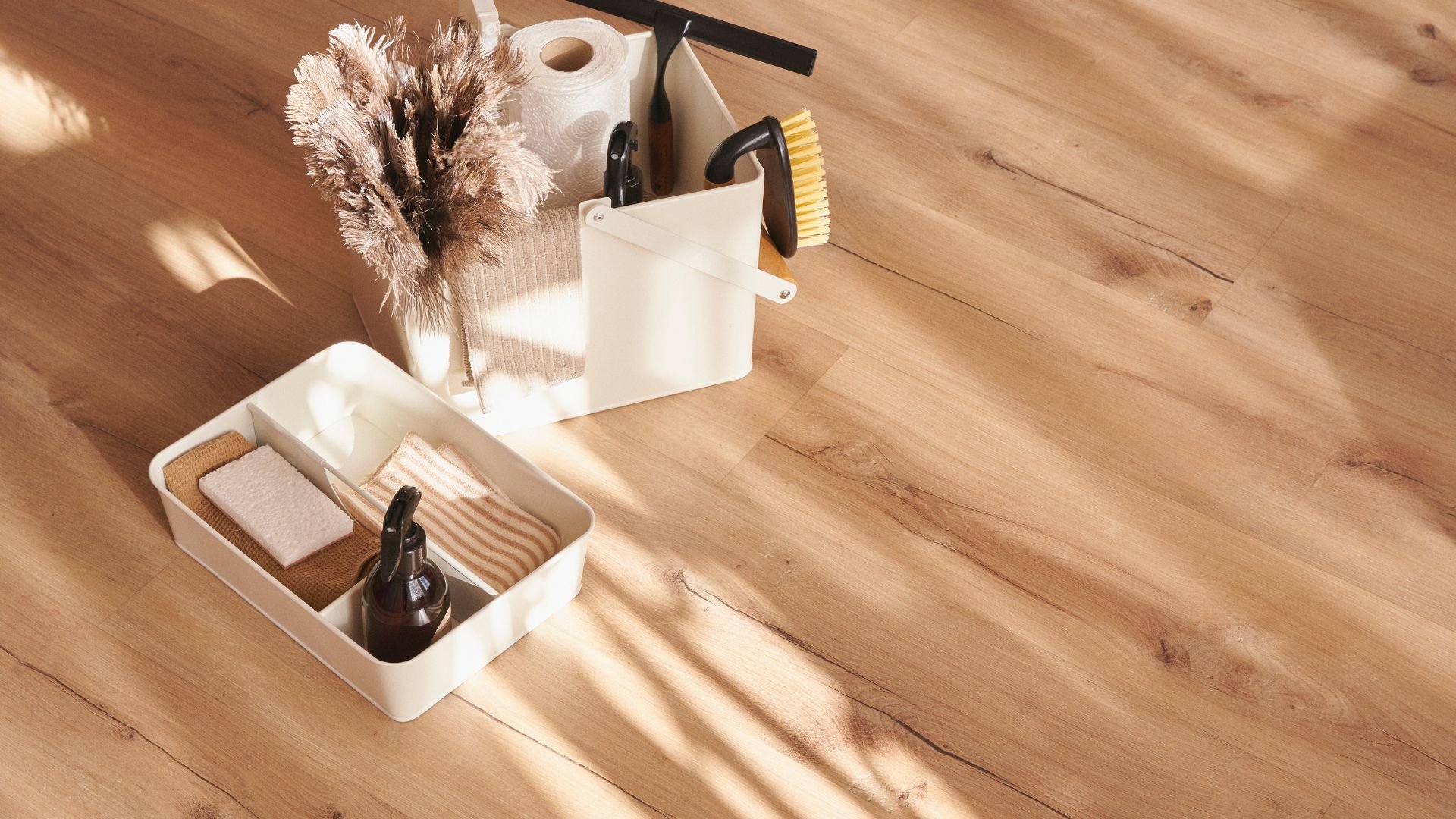 Cleaning supplies and feather duster on wooden surface with soft shadows