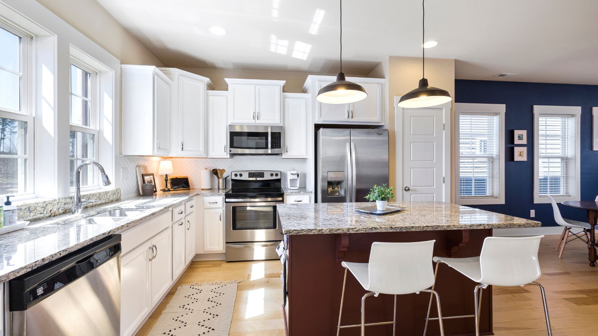 Modern white kitchen with granite countertops, stainless steel appliances, island